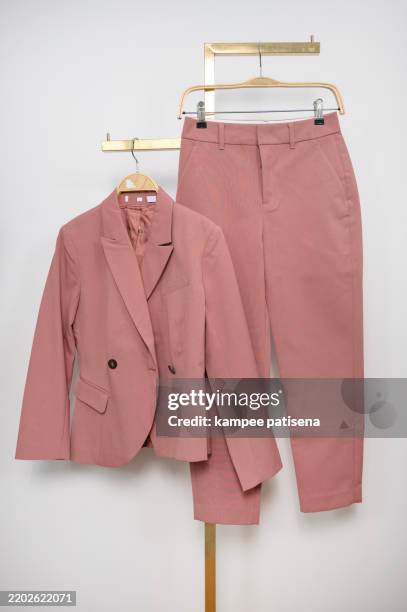 a pink suit and pants are hanging on a hanger - trousers stock pictures, royalty-free photos & images