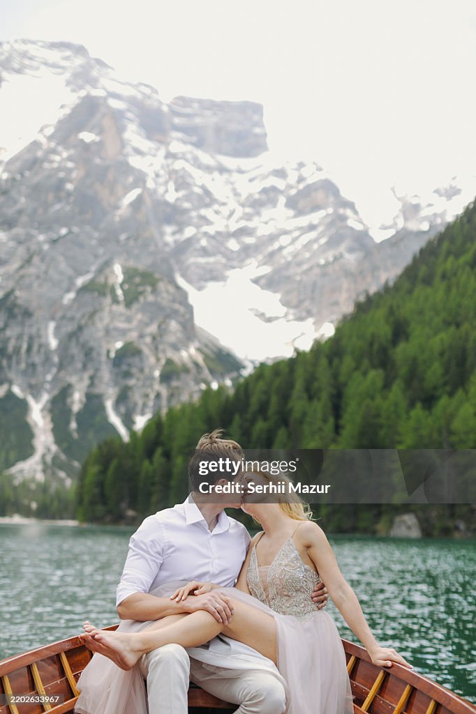 A carefree boat ride of a couple in love on the crystal-clear lake amidst the Dolomite mountains.