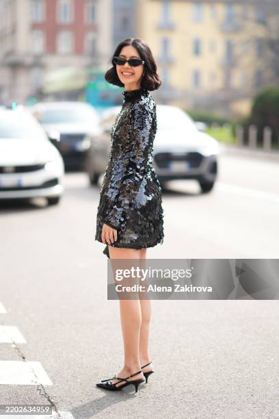 Proud Oranicha Krinchai is seen wearing a black long-sleeve mini dress covered in sequins, black slingback heels, black sunglasses, a black clutch...