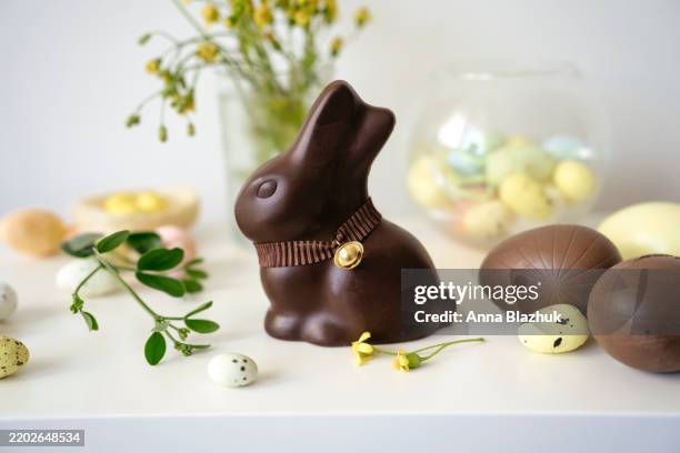 chocolate easter bunny, eggs, flowers and candies. colorful spring festive table setting for easter - conejo de pascua fotografías e imágenes de stock