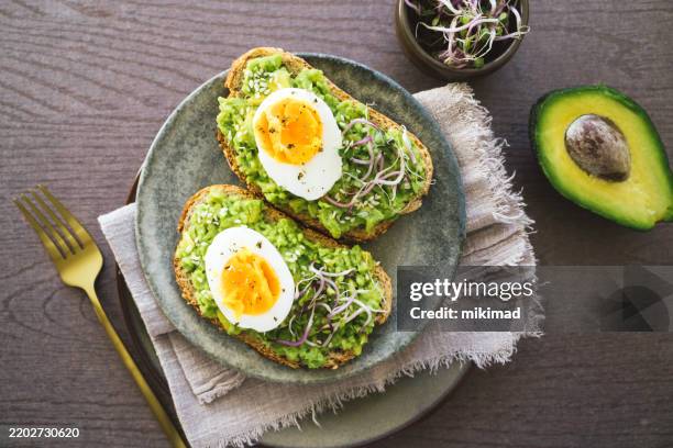 sabrosa tostada de aguacate con huevos escalfados en plato - brunch fotografías e imágenes de stock