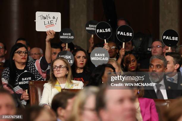 Democrats hold protest signs US President Donald Trump speaks during an address to a joint session of Congress at the US Capitol in Washington, DC,...