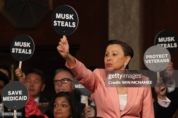 Representative Nydia Velázquez holds a "Musk Steals" protest sign with fellow Democrats as US President Donald Trump speaks during an address to a...
