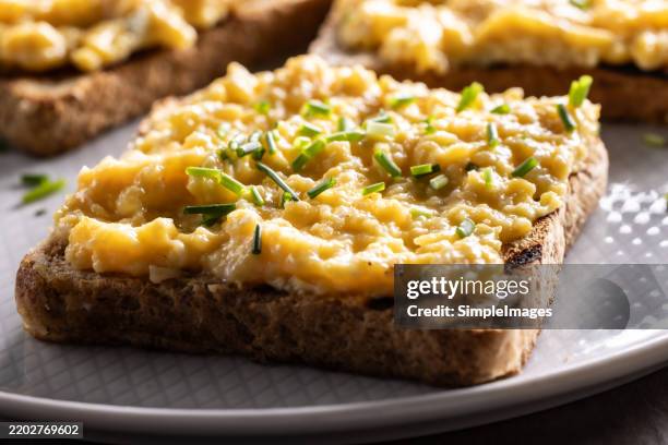 toasted sandwich breads with scrambled eggs and chives on a plate as a healthy breakfast - roerei stockfoto's en -beelden