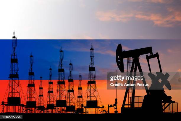 oil field with rigs on the background of the russian flag - russische kultur stock-fotos und bilder