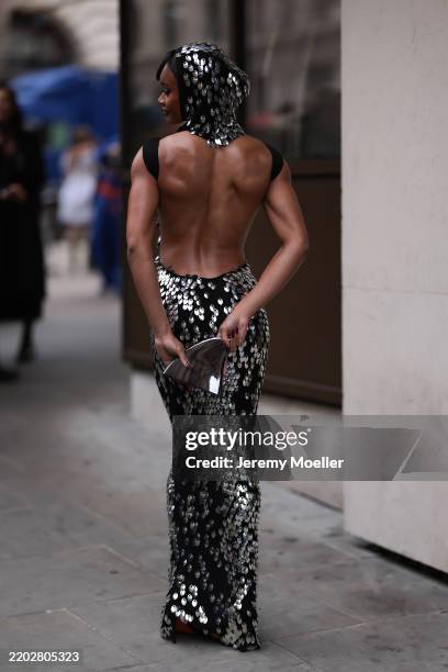 Fashion Week Guest seen wearing a black backless and silver glittery long dress, matchy balaklava and leather handbag in black, black heels outside...