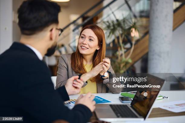 businesswoman talking with a businessman in a modern office during a meeting - woman-man-handshake-across-table stock pictures, royalty-free photos & images