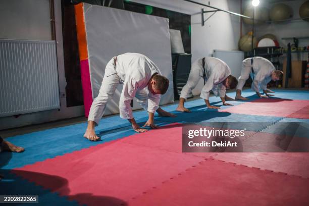 a group of fighters practice aikido and do stretching exercises - dojo stock pictures, royalty-free photos & images