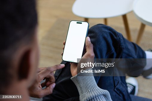 Hombre joven relajándose en el sofá usando un teléfono inteligente con pantalla en blanco Hombre joven relajándose en el sofá usando un teléfono inteligente con pantalla en blanco