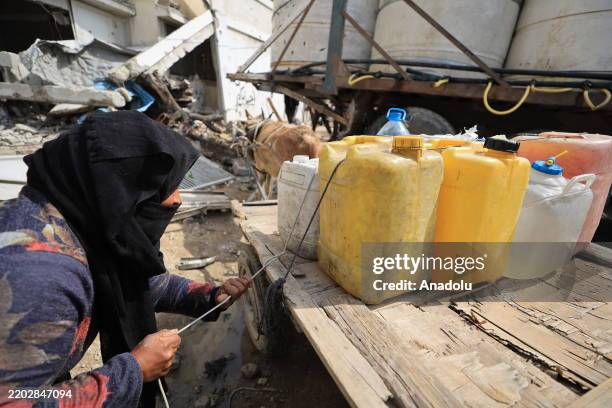 Displaced Palestinians in the Shujaiyya neighborhood of eastern Gaza meet their water needs by filling containers from tanker deliveries on March 05,...