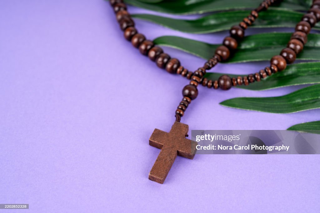 Rosary Beads on top of Palm Leaves Purple Background