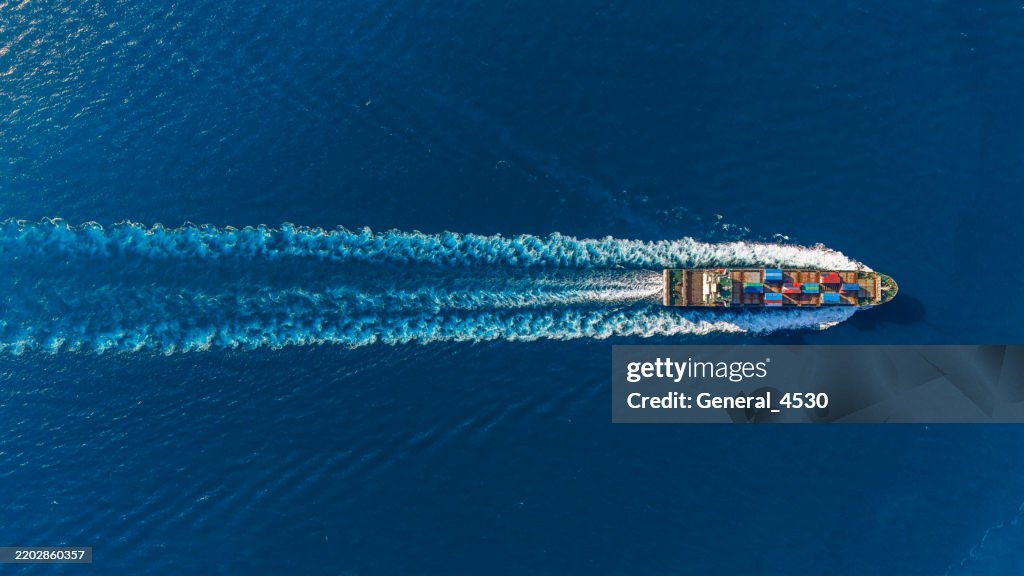 Aerial top view container ship full speed with beautiful wave pattern at blue sea.