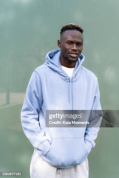 young black man smiling with hands in pockets, wearing blue hoodie - sweatshirt stock pictures, royalty-free photos & images