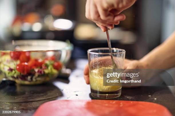 closeup of teenage boy preparing vinaigrette dressing - he is mixing the ingredients in a glass. - salad dressing stock pictures, royalty-free photos & images