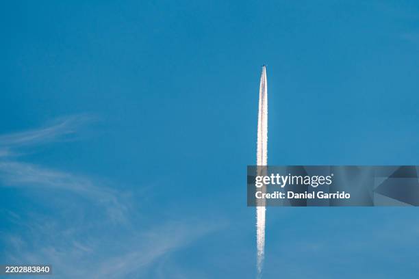 plane flying among clouds, leaving a wake resembling a rocket. - rocket engine stock pictures, royalty-free photos & images