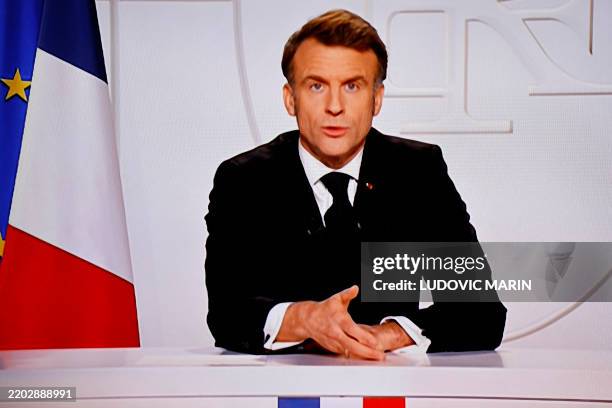 This photograph taken on March 5 shows a television screen broadcasting France's President Emmanuel Macron addressing a live interview on French TV...