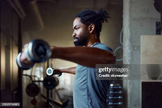 determined black sportsman exercising with dumbbells in a gym. - tyngdlyftning bildbanksfoton och bilder