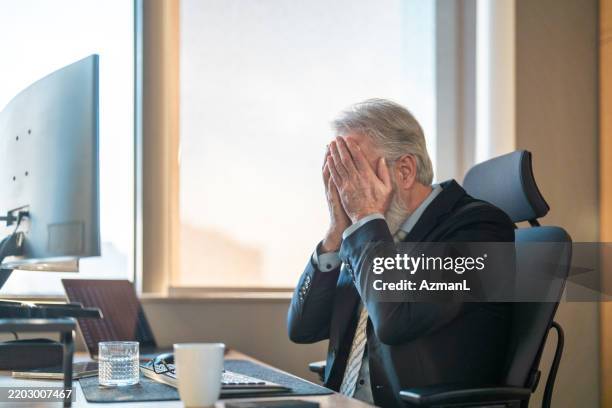 stressed stock broker covering face at office computer during market downturn - stock broker office stock pictures, royalty-free photos & images