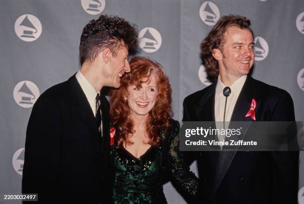 American singer, songwriter and musician Lyle Lovett, wearing a black suit over a white shirt with a black-and-white diagonally striped tie, American...