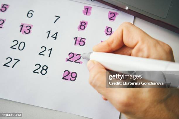 person highlighting important dates on a calendar with a marker - semana imagens e fotografias de stock