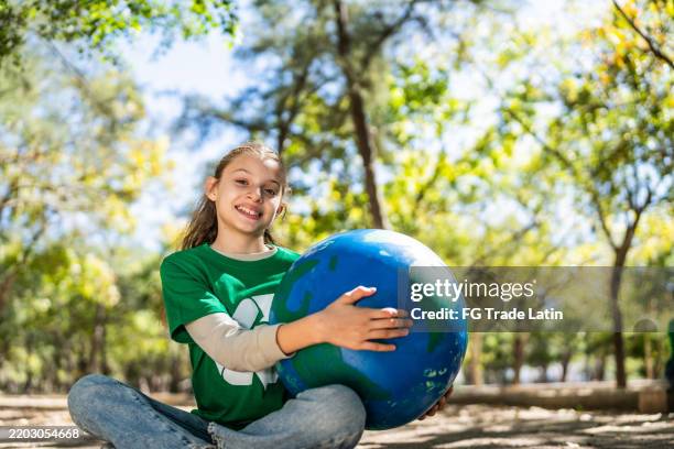 portrait of child recycler girl holding a globe on public park - social responsibility stock pictures, royalty-free photos & images