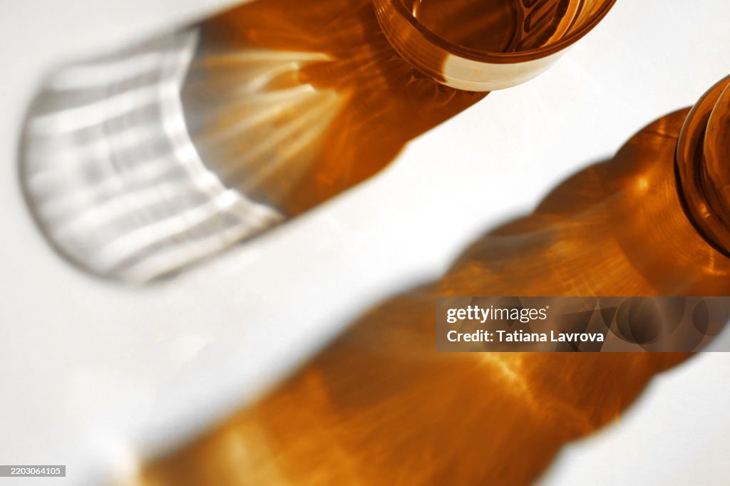 Abstract flat lay with amber colored dishes and glasses on white backdrop