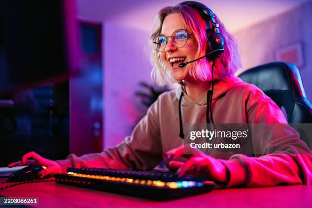 young woman playing a video game on her desktop pc - videospel stockfoto's en -beelden