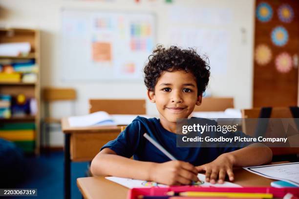 elementary schoolboy sitting at desk, smiling at camera - skolbarn bildbanksfoton och bilder
