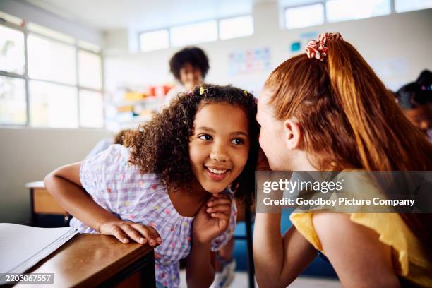 colegiala con el pelo rojo susurrando a un compañero de clase en clase, de cerca - cotilleo fotografías e imágenes de stock