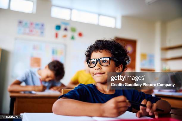 schoolboy sitting at desk, smiling, looking sideways - edifício escolar imagens e fotografias de stock