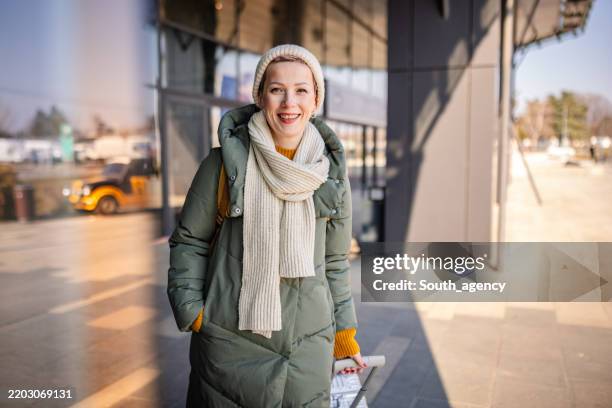 young woman enjoying her time at the bus station while waiting for transportation to her next destination - scarf stock pictures, royalty-free photos & images
