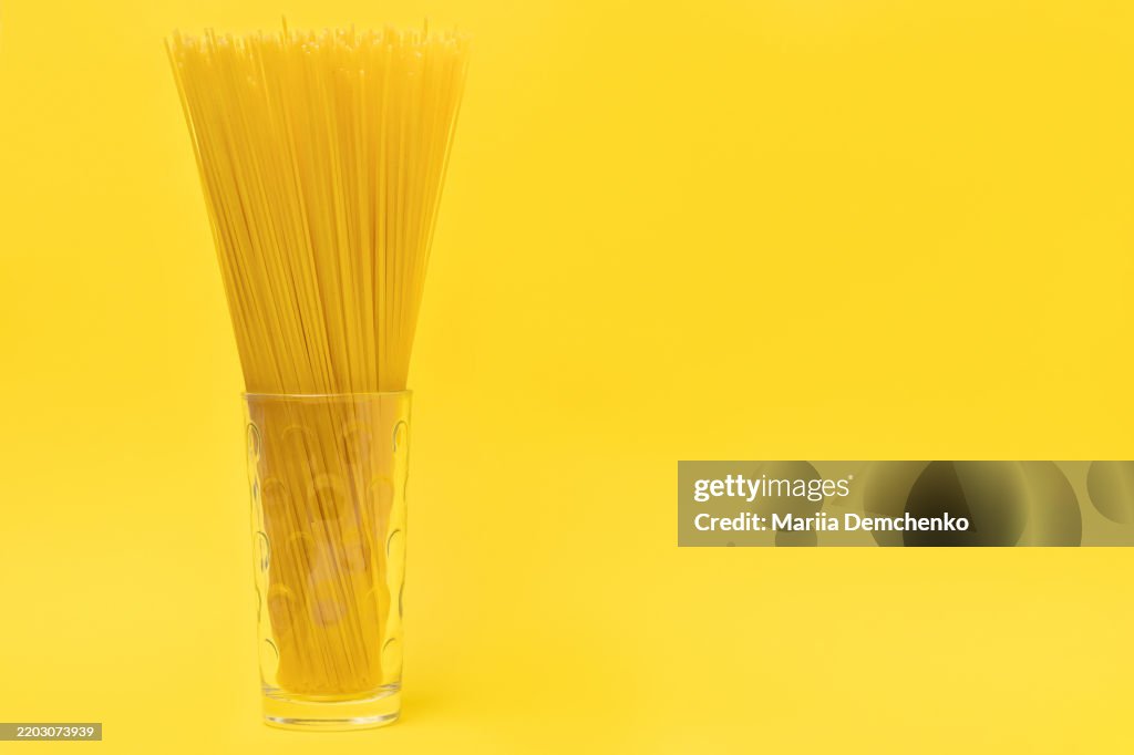 Uncooked raw spaghetti pasta on yellow background