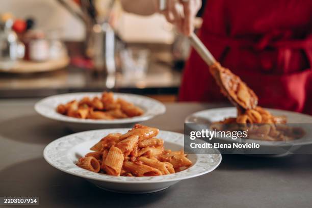 the chef in the kitchen prepares italian penne pasta with tomato sauce with olives and parmesan cheese - italiaanse keuken stockfoto's en -beelden