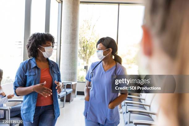 doctor and patient talking in a medical clinic waiting room - epidemic stock pictures, royalty-free photos & images