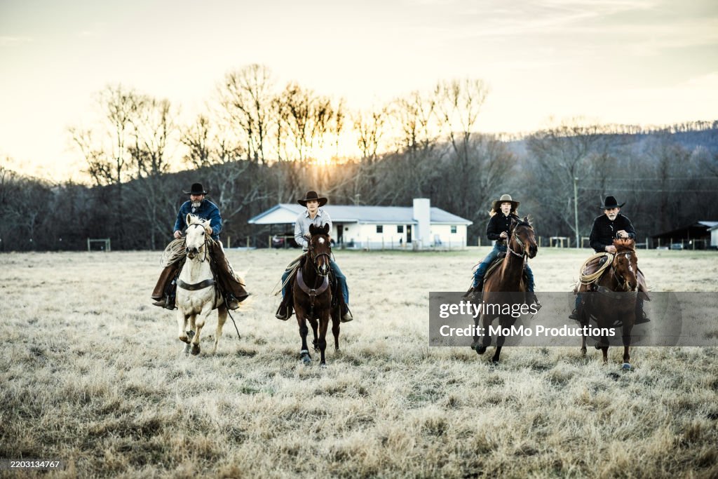 Multi-generational family of cowboys riding horses at sunset