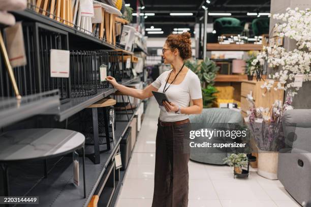 femme concentrée sélectionnant des articles sur l’étagère des meubles - équipement domestique photos et images de collection