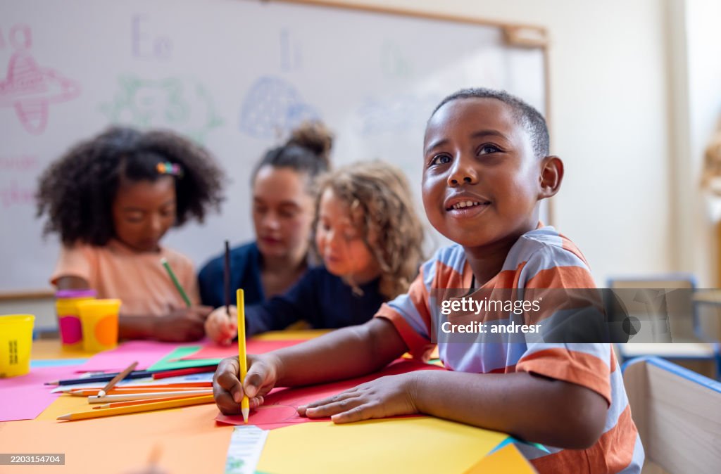 Happy schoolboy drawing in class at the kindergarten