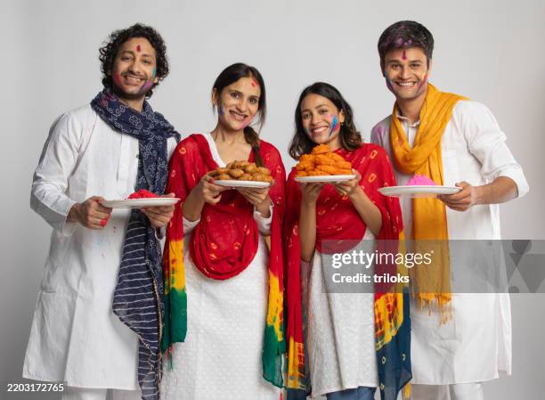 couples celebrating holi festival with sweets and paints on white background - mithai stock pictures, royalty-free photos & images