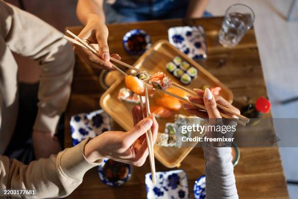 young friends in sushi bar - chopsticks stock pictures, royalty-free photos & images