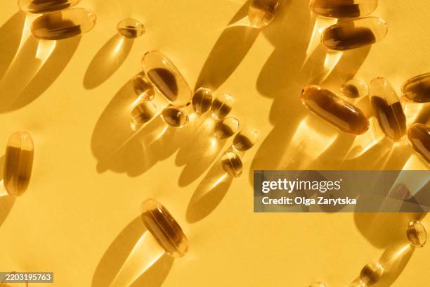 fish oiled capsules on yellow background. soft capsules of omega 3, 6, vitamin d. - vitamin e stock pictures, royalty-free photos & images