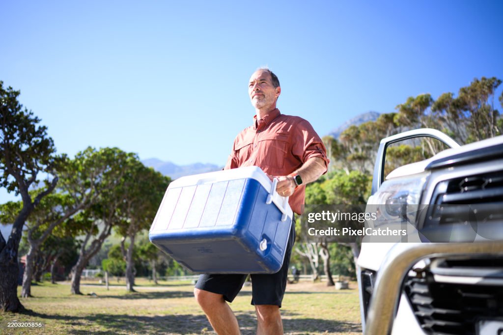 Low angle portrait man carrying cooler box