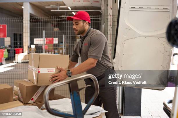 male worker holding cardboard box while loading in van - loading boxes stock pictures, royalty-free photos & images