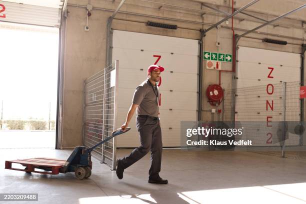 warehouse worker pulling empty hand truck - pulled in different directions stock pictures, royalty-free photos & images