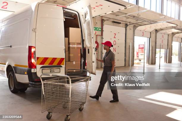 mature delivery woman closing door of loaded delivery van - loading dock stock pictures, royalty-free photos & images