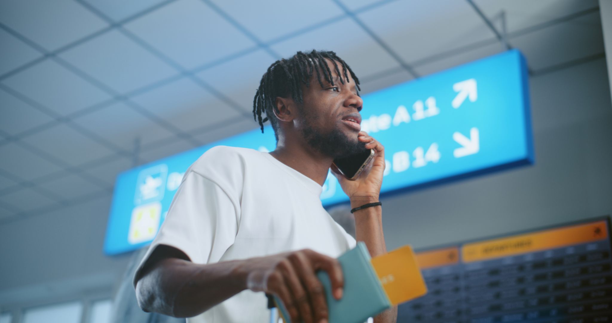 Airport Terminal: Man Talking by Phone, Checking Flight Information on Arrival and Departure Display Airport Terminal: Man Talking by Phone, Checking Flight Information on Arrival and Departure Display