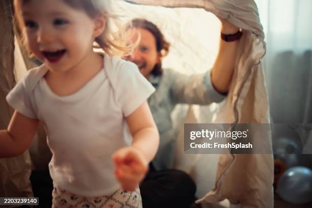 enfant souriant jouant à l’intérieur avec ses parents dans un environnement amusant et douillet - flouté photos et images de collection