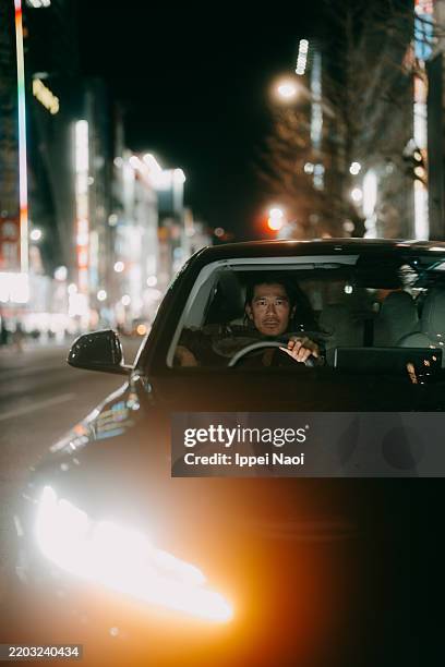 man driving car at night in city, tokyo - auto cool stock-fotos und bilder