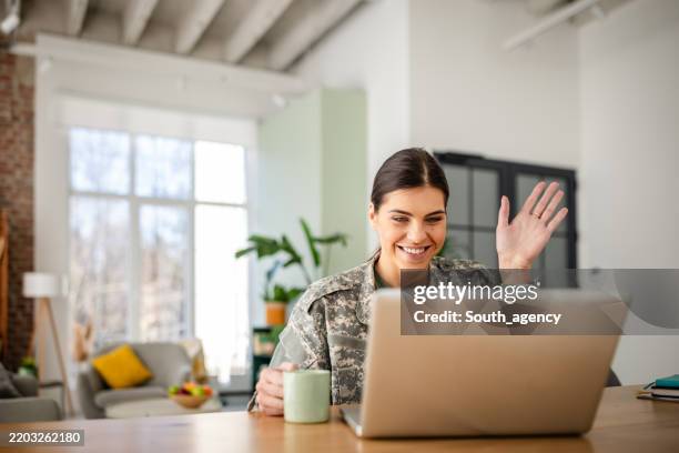 young woman soldier connects with family at home while in military uniform using technology - military uniform stock pictures, royalty-free photos & images
