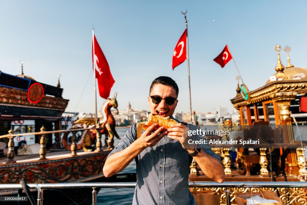 Happy man eating Balik Ekmek fish sandwich in Istanbul, Turkey