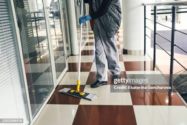 worker cleaning polished floor in modern commercial building interior - impresa di pulizie foto e immagini stock